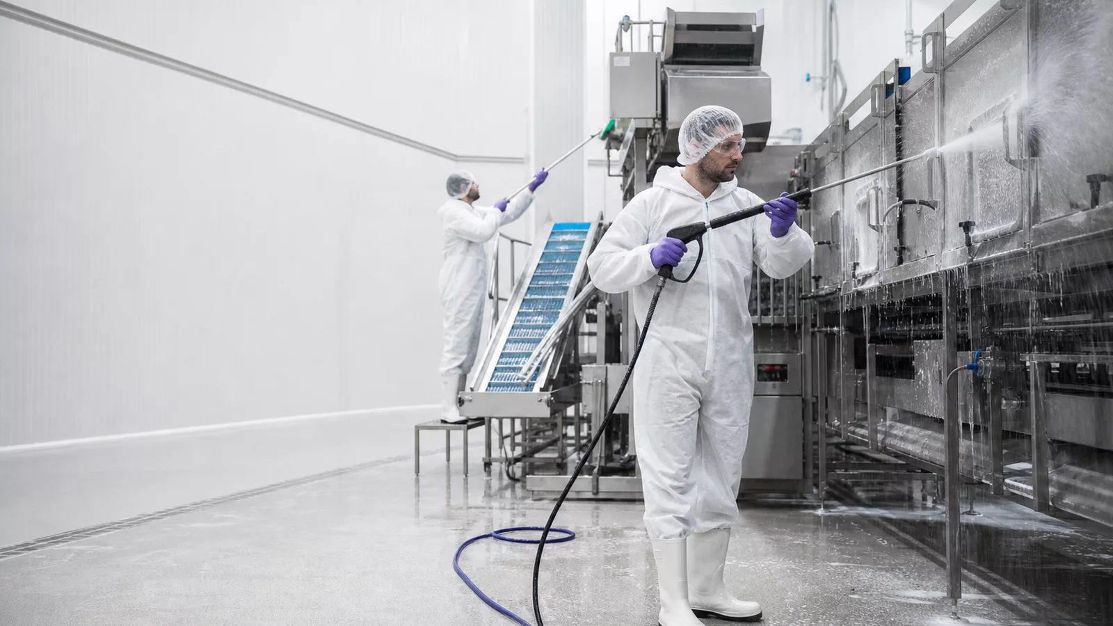 Specialist cleaners sanitising food production equipment in a hygienic factory