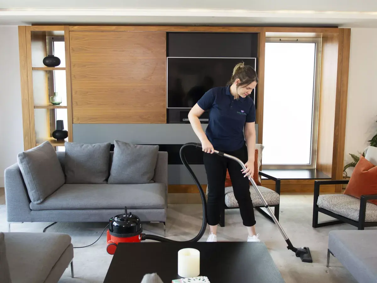 UF Cleaning housekeeper professionally vacuuming a furnished living room