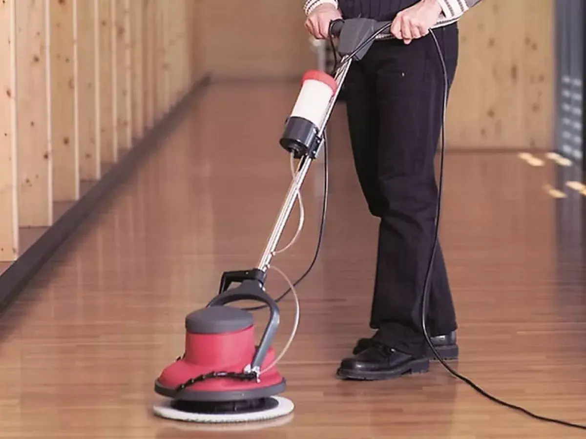 Professional operating a rotary floor polishing machine on an office hard floor
